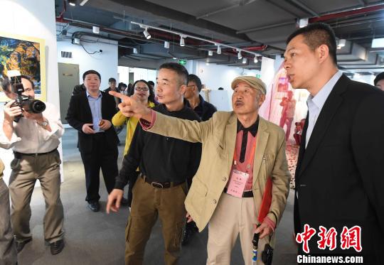 85歲高齡的臺灣著名攝影家許捷芳(右二)向來賓介紹自己參展攝影作品的創作經過。　記者劉可耕 攝