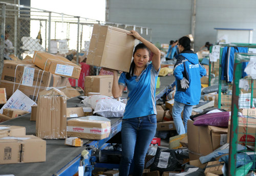 资料图片:一家快递公司工作人员在广西南宁市玉洞物流中心忙著搬运