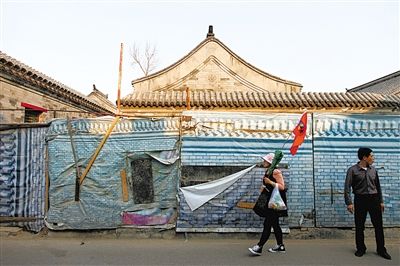 昨日，小石碑衚同，一位導遊帶著遊客走過建築圍擋。西城區今年計劃啟動什剎海舊城保護示範項目。新京報記者