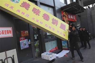 昨日下午，豐台區食藥監局執法人員對涉嫌違法經營的店舖招牌進行拆除。新京報記者 吳江攝