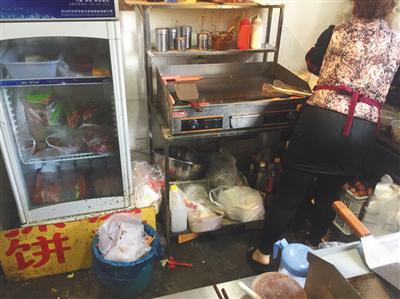同時入駐了三家外賣平臺的“臺灣手抓餅”店內，老闆娘正在加工食物，店內衛生條件差。後該店被查出無證經營。新京報記者 張越攝