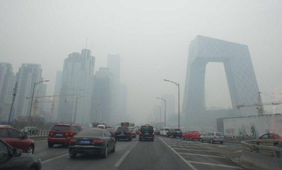 　　2月21日，車輛行駛在霧霾籠罩的北京街頭，中央電視臺新址大樓依稀可見。