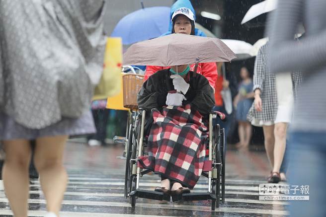 臺灣中部以北從中午開始雨勢增大，連坐輪椅外出的民眾都撐起傘具避雨。(中時電子報圖張鎧乙攝)