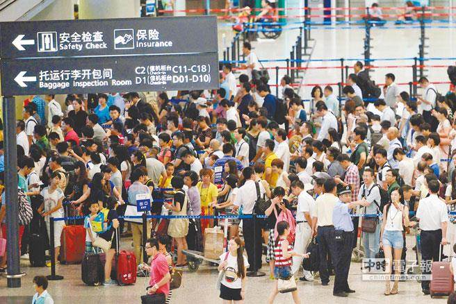 兩岸春節加班機明天上午8時開賣。圖為旅客去年春節期間在上海虹橋機場排隊換票。(臺媒取自新華社)