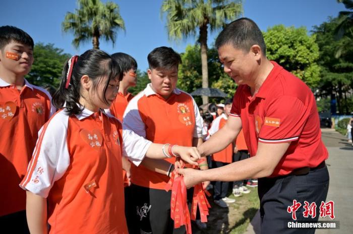 資料圖：廣西華僑實驗高中的教師為高三學子繫上紅絲帶，盼望學子高考必勝。 俞靖 攝