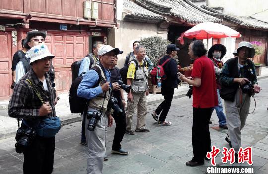 雲南省攝影家協會副主席徐晉燕(紅衣)在雲南巍山古城向兩岸攝影家介紹古城淵源。　周志鴻 攝