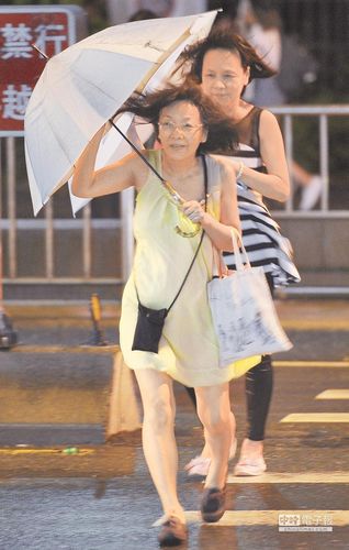 受到“鲇魚”颱風的影響，臺北地區9月26日入夜之後風勢轉強，路人撐著傘快步越過斑馬線。來源：臺灣《中國時報》