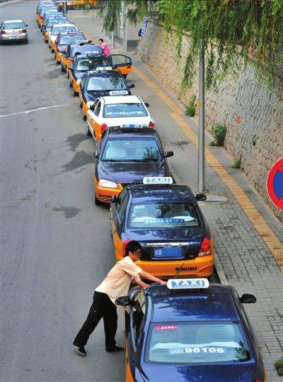 6月27日，在早高峰期間，許多計程車停在德勝門附近。司機利用這個時間段擦車、吃飯或者休息。 新華社發