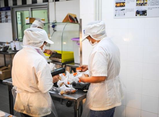 工作人員在沃爾瑪深圳洪湖店對熟食進行包裝（2014年8月8日攝）。新華社發