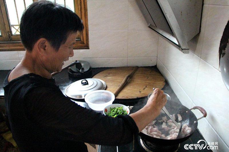 　　余秋明家裏搞起農家樂，正在自家廚房給遊客燒菜。