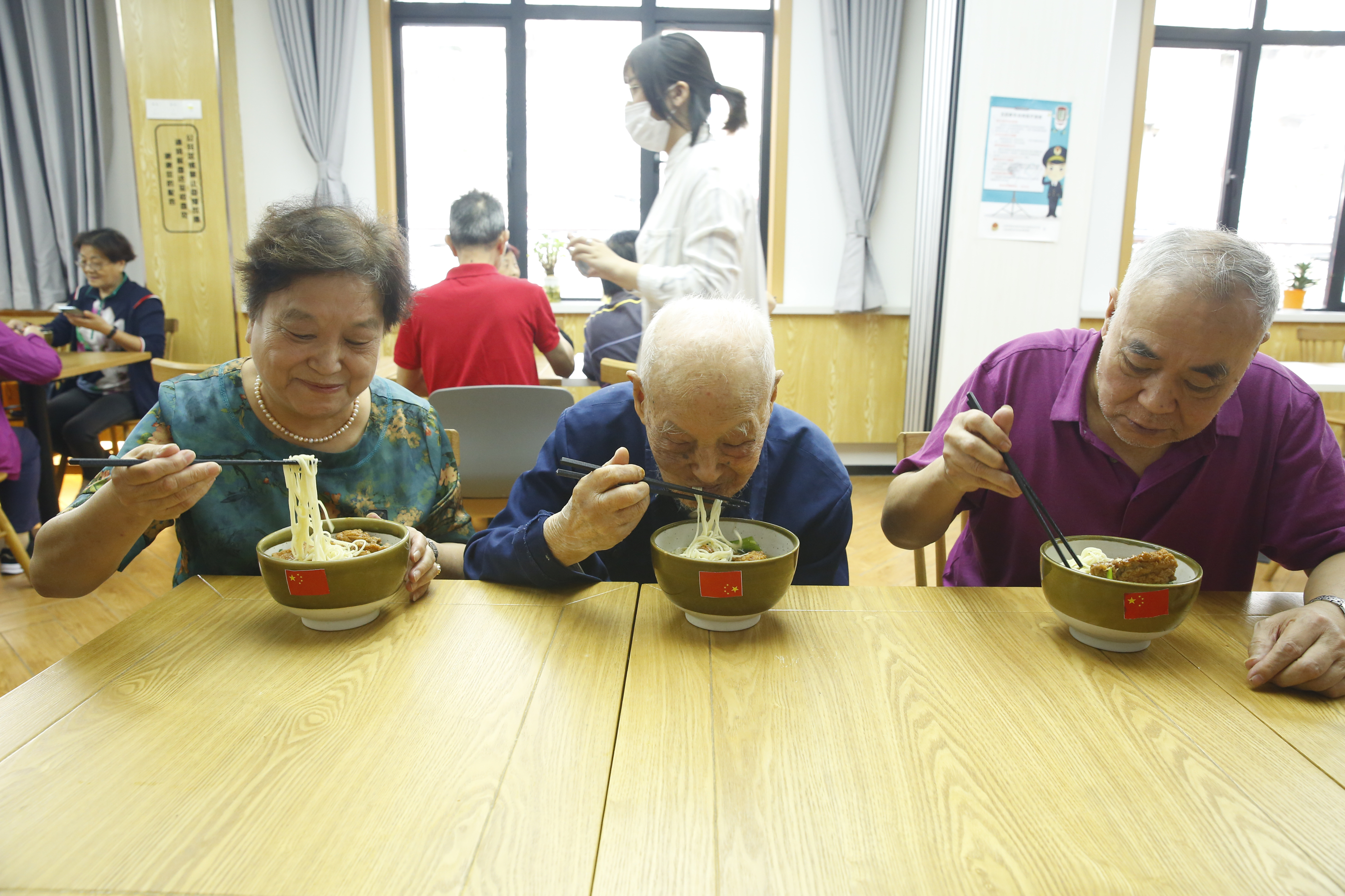 來自普陀區石泉路街道鎮坪居民區106歲的李佩印老人（前排右二）正在和居民朋友一起吃國慶面。石泉路街道 供圖
