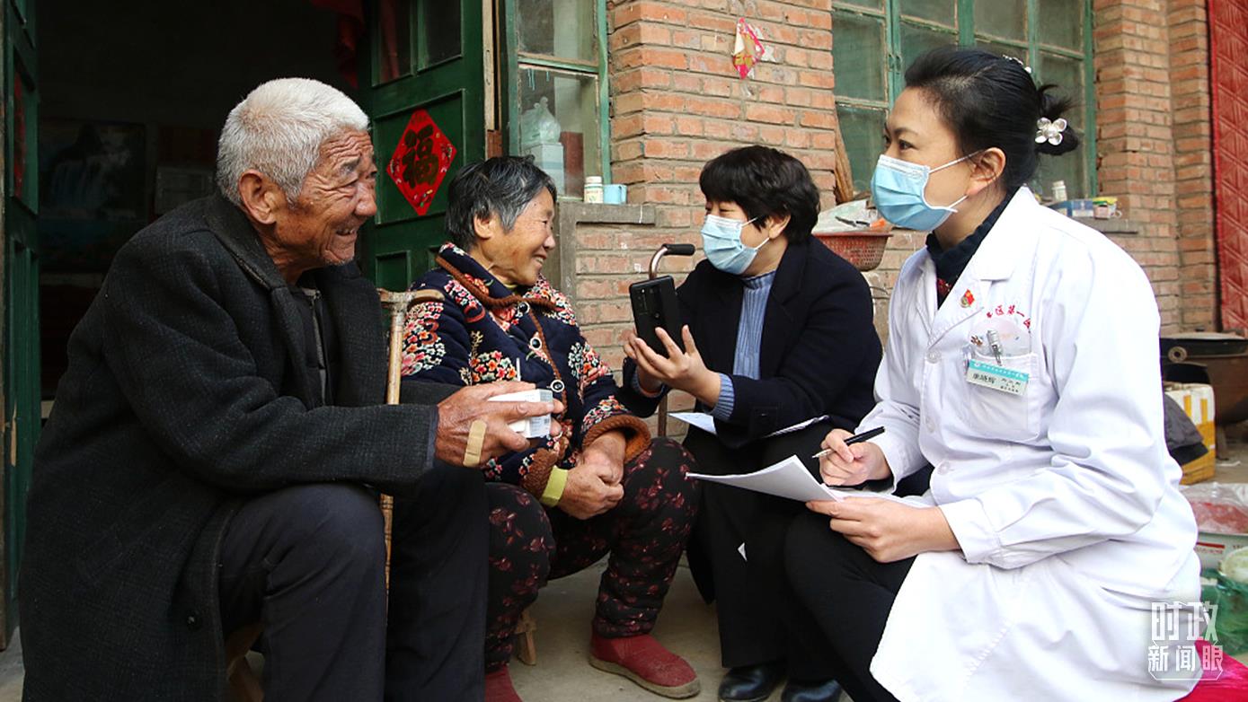 △2021年12月，河北邯鄲，工作人員為村民講解醫保政策。（圖/視覺中國）