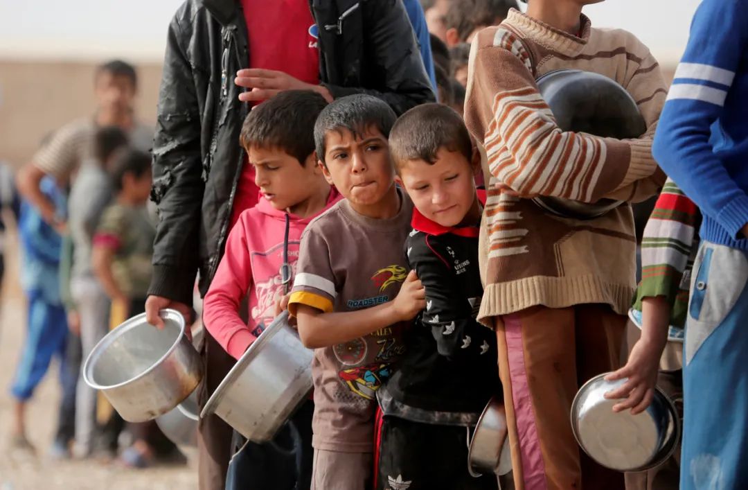 △伊拉克摩蘇爾一所難民營裏，無家可歸的民眾排隊領取食物。