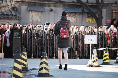 15日,中央戲劇學院,一位身穿裙子、腳蹬高跟鞋、背著卡通圖案書包的藝考生在結束考試後走向校門,門外更是有很多等待孩子的家長。