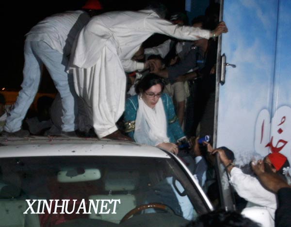 10月19日，在巴基斯坦卡拉奇，巴前總理貝�布托（中）在爆炸發生後轉移到防彈車。據巴基斯坦電視臺報道，當天淩晨在南部港口城市卡拉奇，剛剛回國的前總理貝�布托所乘坐的車輛附近發生自殺式爆炸襲擊，貝�布托本人安然無恙。 新華社發