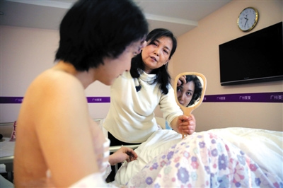 2015年3月5日，廣州，剛做完胸部手術的劉霆還未康復，母親拿著鏡子給劉霆看。