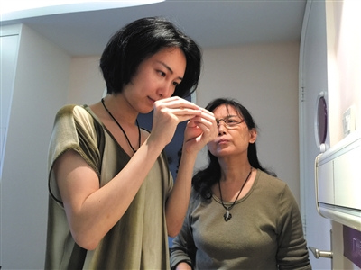 2015年4月6日，廣州，完成變性手術的劉婷，在病房內幫母親穿針，陸永敏為女兒縫補裙子。