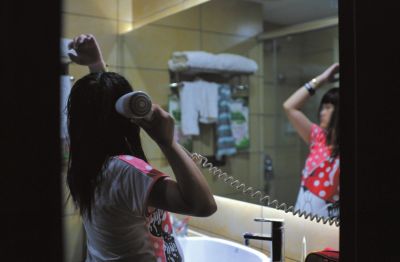 右圖：深圳一家賓館內，很久都沒能洗澡的思思終於洗了個熱水澡，放鬆地為自己吹乾頭髮。