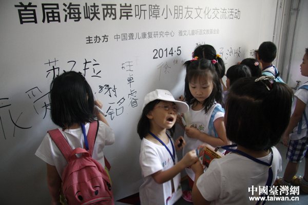 來自臺灣的聽障小朋友在展板上簽下自己的名字，這兩位可愛的小蘿莉因為誰先用筆的問題起了點小爭執