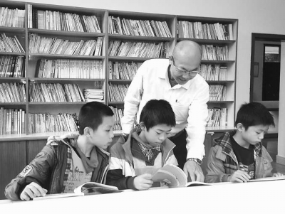 遊岳勳在指導小學生學習課外讀物。